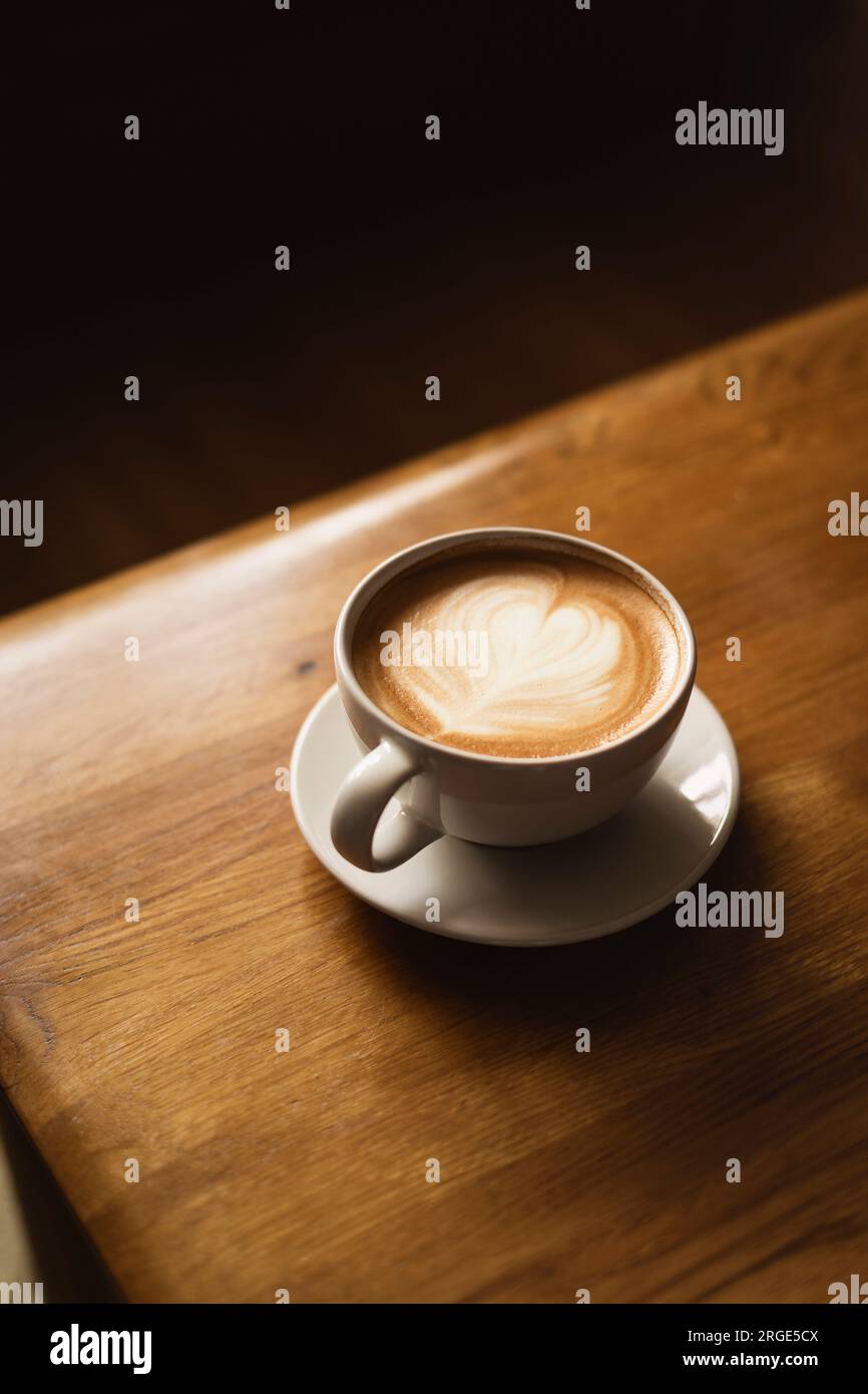 Coffee in white cup on wooden table, with spoon. Stock Photo