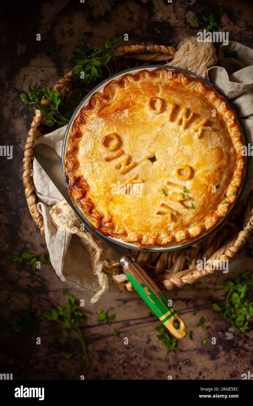 A sausage pie made with shortcrust pastry and decorated with pastry letters spelling oink oink oink. Stock Photo