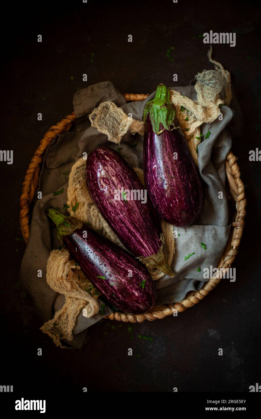 Three aubergines in a basket. Stock Photo