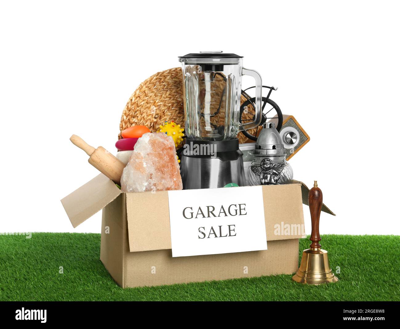 Box with sign Garage Sale and different stuff on green grass against ...