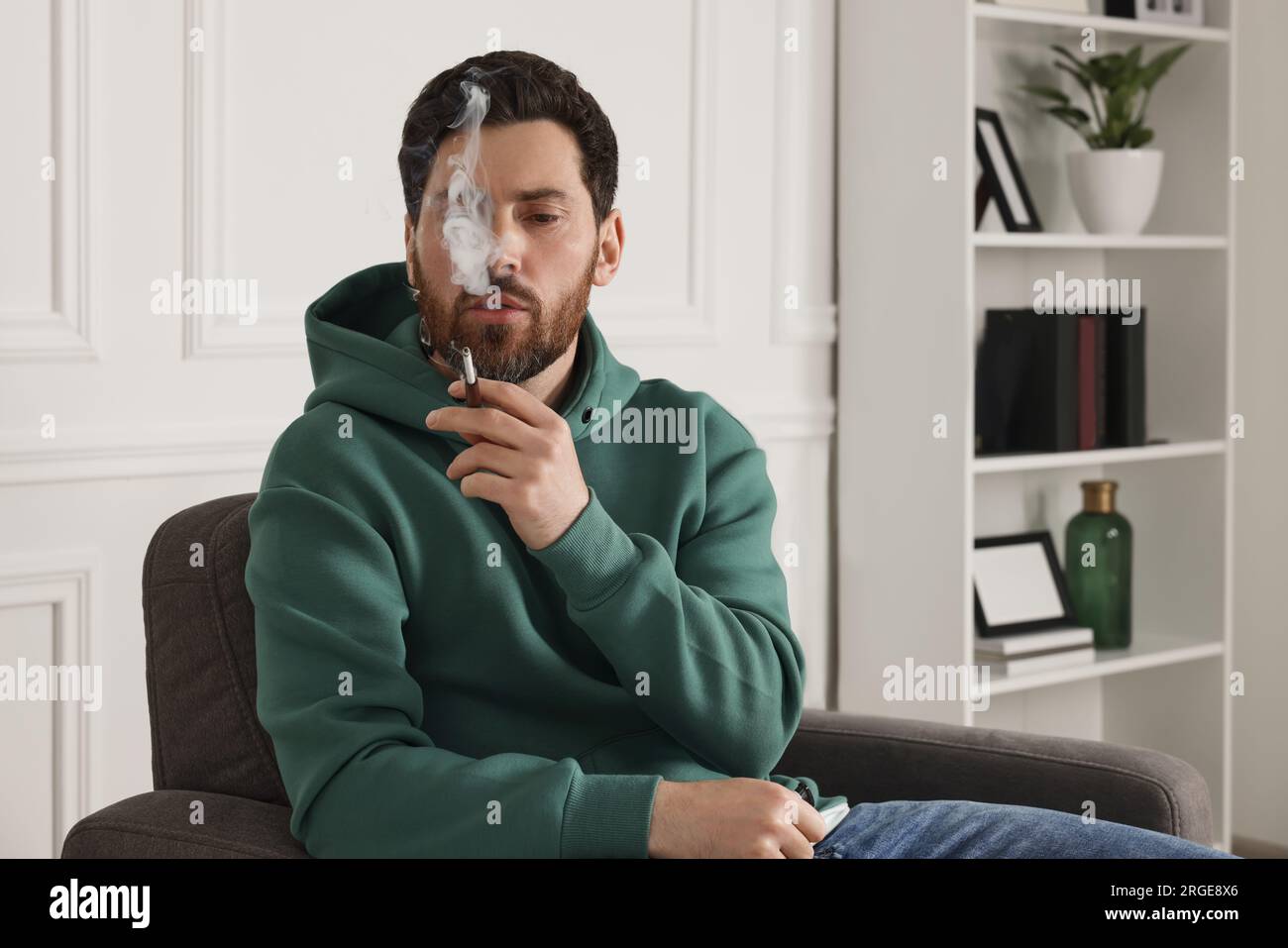 Man using cigarette holder for smoking indoors Stock Photo