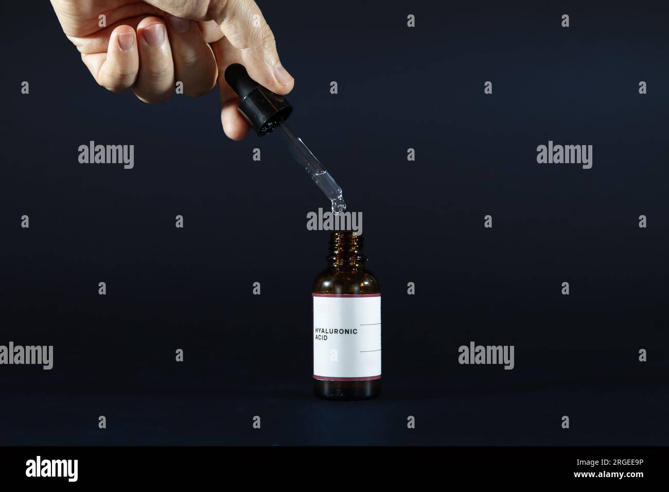 Picture of hands holding a pipette of hyaluronic acid isolated on black