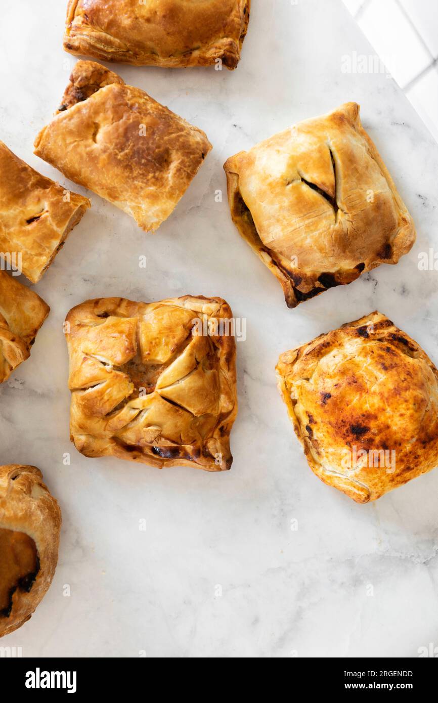 Delicious sweet and savory pastries beautifully displayed on a clean white slate surface, enticing and delectable. Stock Photo