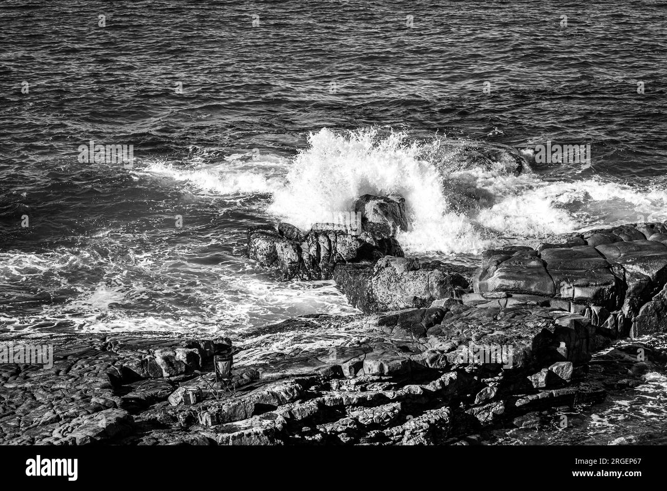 Big splash causing by the wave hitting the rock formation Stock Photo