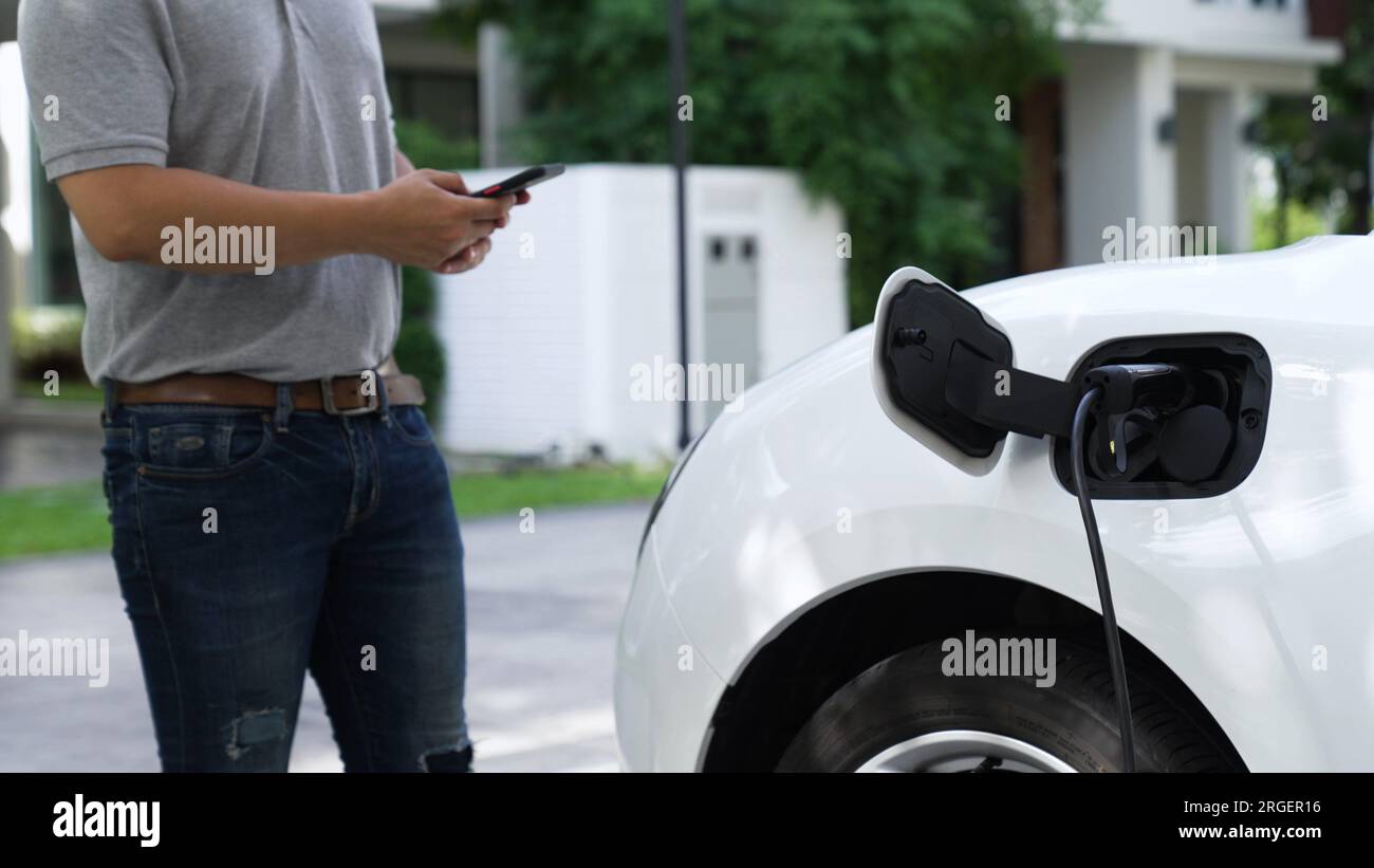 Electric car plug into home charging station to recharge battery with