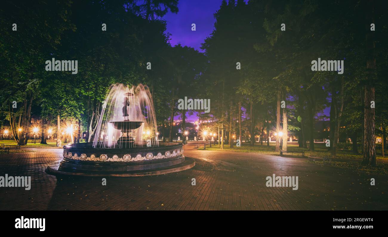 A fountain with blurred streams of water in a night park illuminated by ...