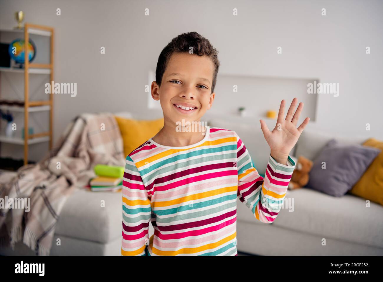 Portrait photo of cheerful friendly small guy waving hand friendly picture  spend time playroom entertainment isolated indoors background Stock Photo -  Alamy, image size:1300x956