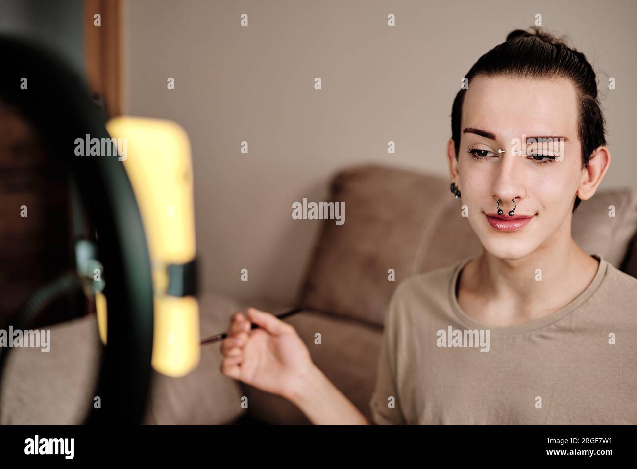 Gay man making up while recording with the mobile Stock Photo
