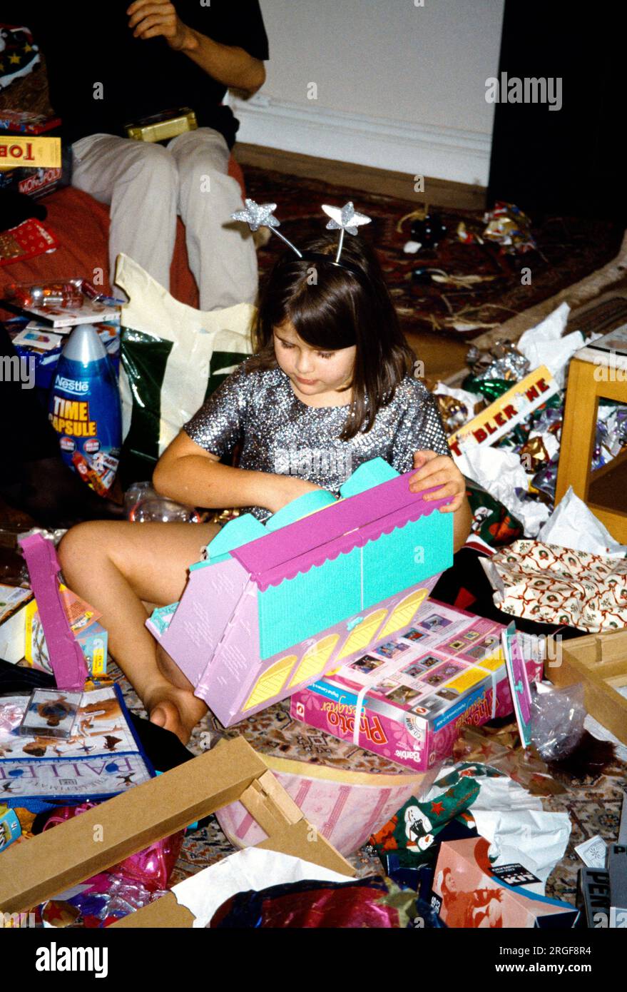 Child Opening Present a Dolls house at Christmas Surrey England Stock Photo