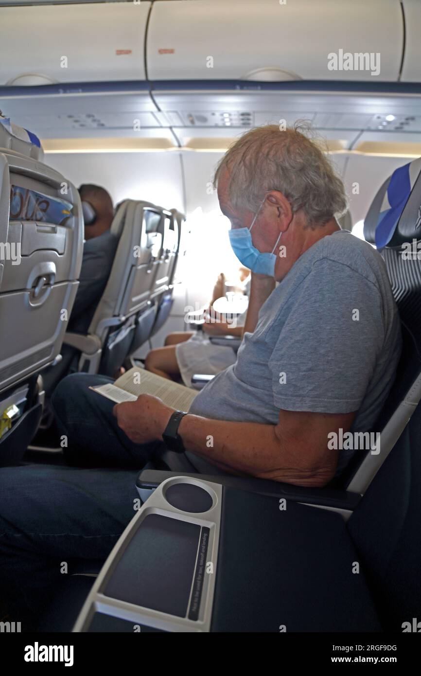 Passenger Wearing a Face Mask Reading a Book Onboard Aegean Airlines