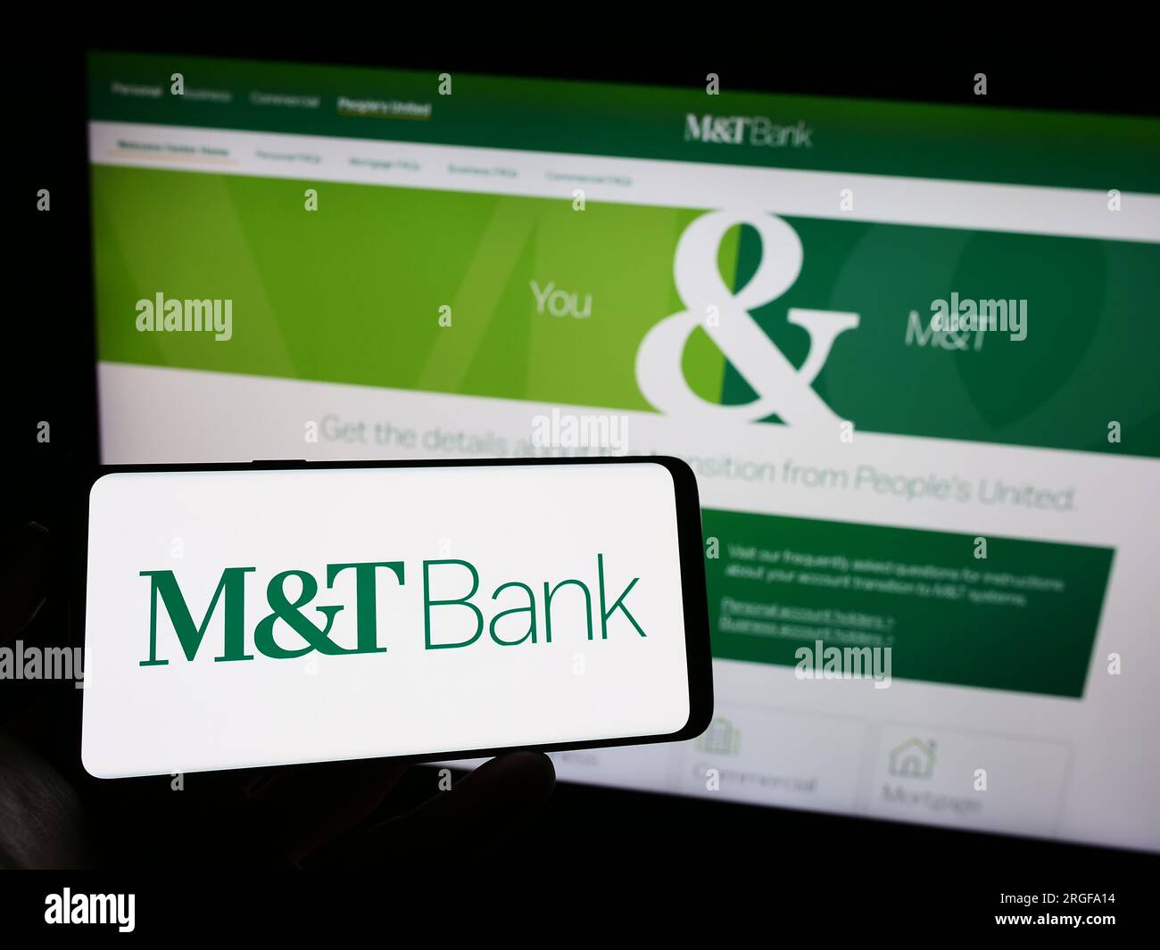 Person holding smartphone with logo of US financial company MT Bank Corporation on screen in front of website. Focus on phone display. Stock Photo