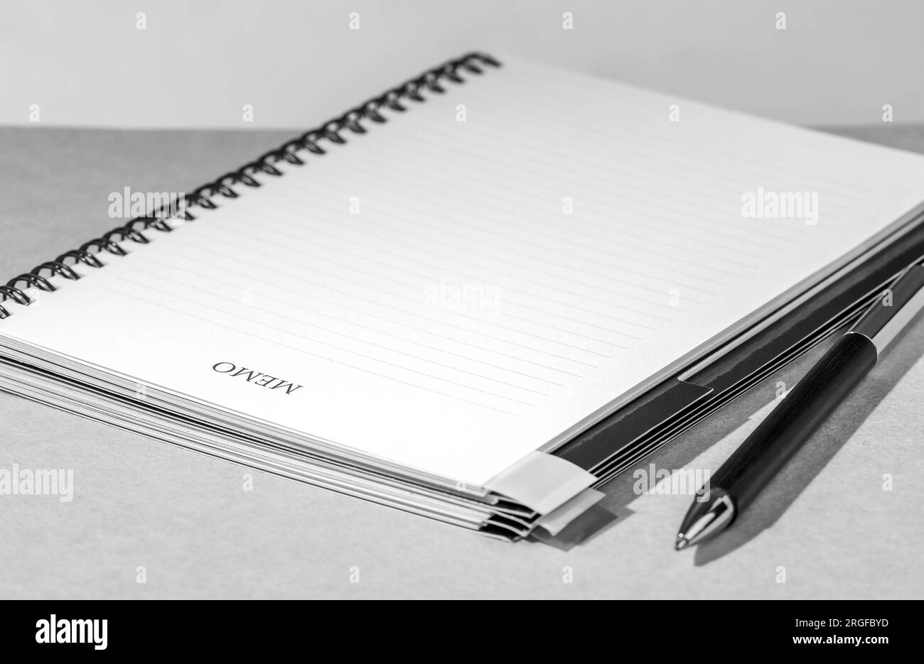Blank sheet of memo notebook with a spiral and pen on a gray textured table Stock Photo