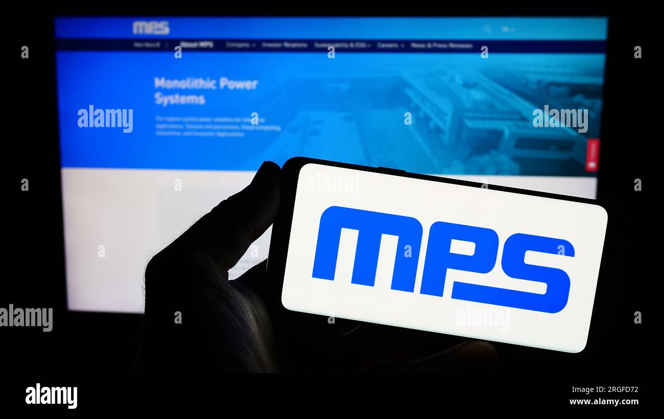 Person holding smartphone with logo of US company Monolithic Power Systems Inc. (MPS) on screen in front of website. Focus on phone display. Stock Photo