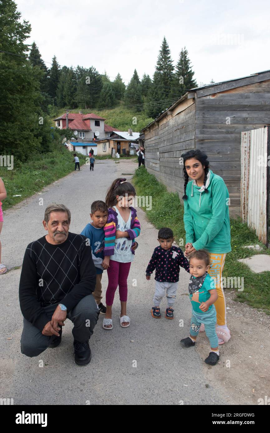 Romany gypsy family, grandfather, daughter and grandchildren. Families often have at least six children, multi generational house in background. Gypsy settlement on the outskirts of Sumiac, Brezno District, Slovakia August 2023. 2020s HOMER SYKES Stock Photo