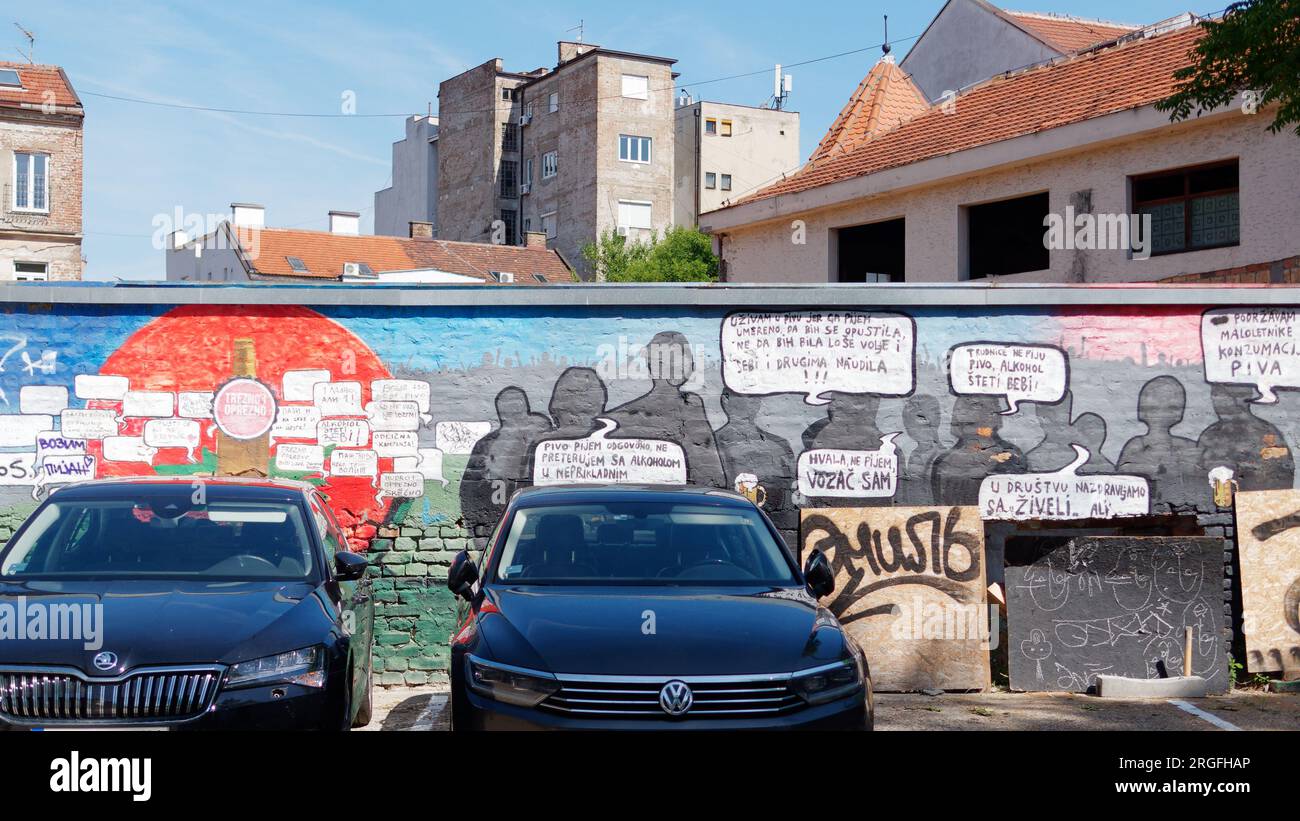 Car park with illustrations on thw wall and captions, with buildings behind, in the city of Belgrade, Serbia. August 9, 2023. Stock Photo
