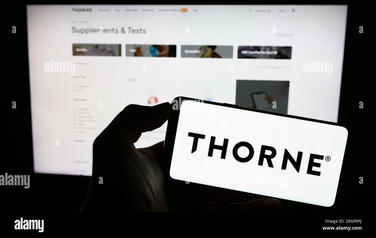 Person holding cellphone with logo of US wellness company Thorne HealthTech Inc. on screen in front of business webpage. Focus on phone display. Stock Photo