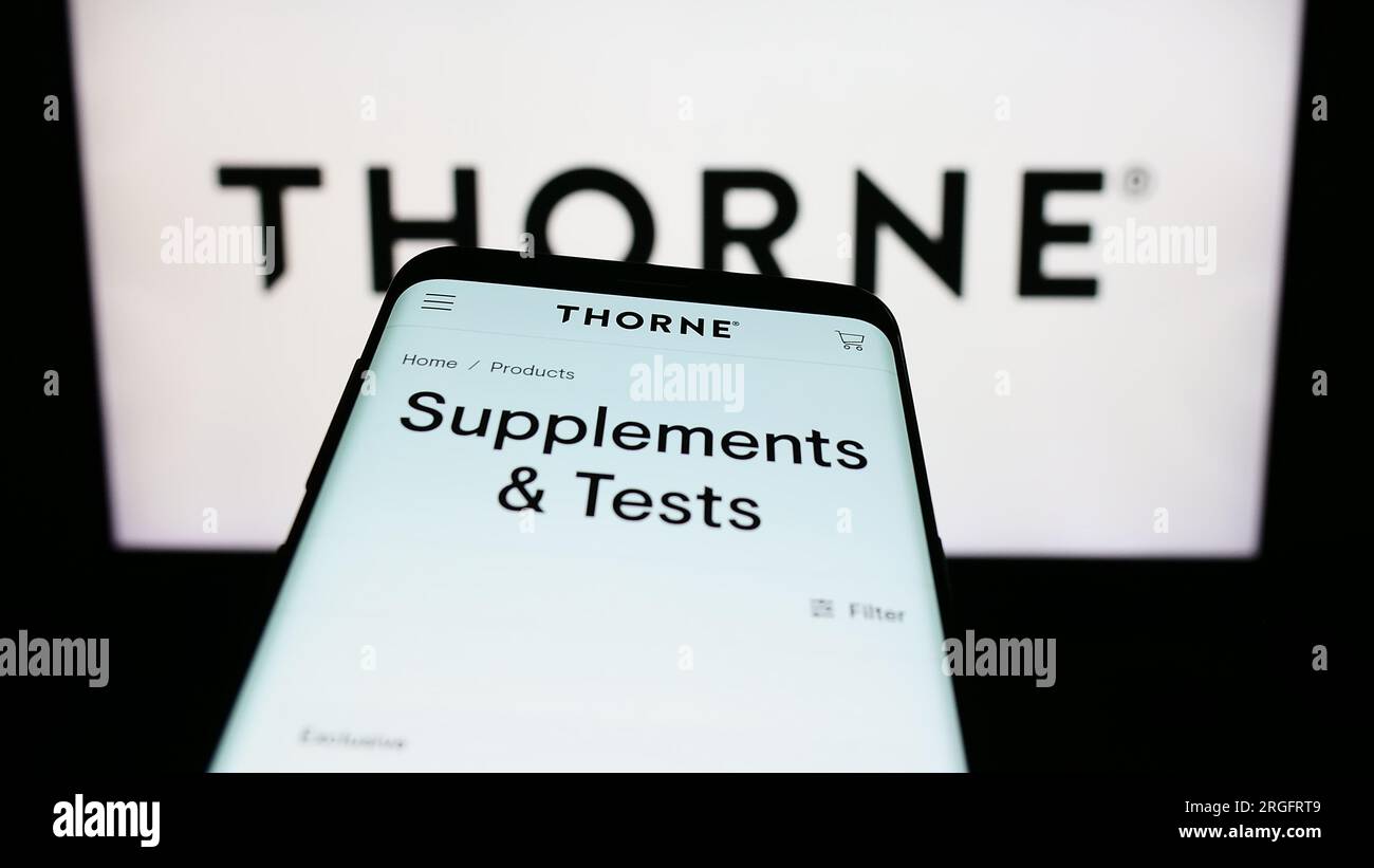 Mobile phone with website of US wellness company Thorne HealthTech Inc. on screen in front of business logo. Focus on top-left of phone display. Stock Photo