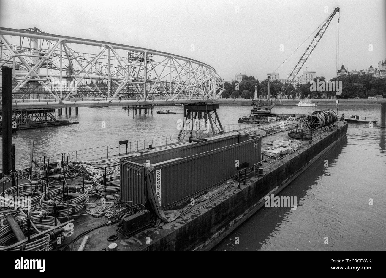 1999 archive black & white photograph of the construction of The London Eye beside the River Thames, London.  The large wheel is laid flat across a section of the river before being hoisted through 90 degrees into a vertical position. Stock Photo