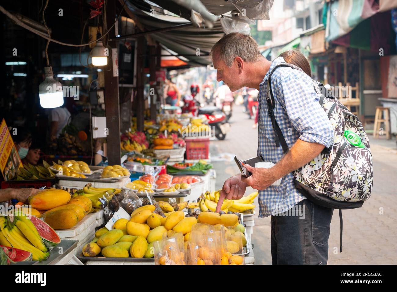 Tourists looking at fruit for sale in Chiang Mai market stalls Stock Photo