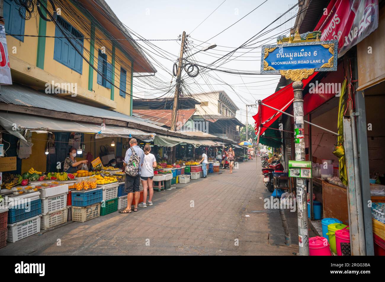 Tourists looking at fruit for sale in Chiang Mai market stalls Stock Photo