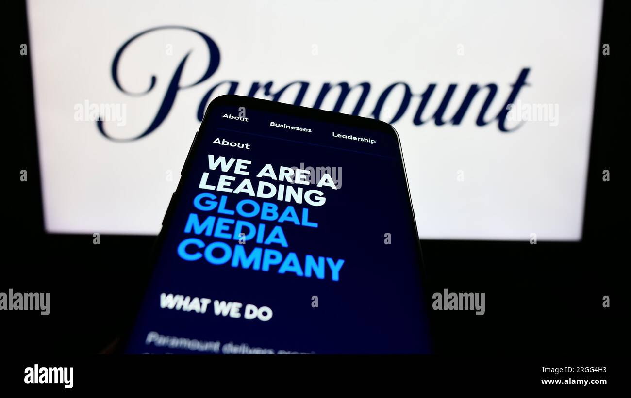 Mobile phone with web page of US entertainment company Paramount Global on screen in front of business logo. Focus on top-left of phone display. Stock Photo