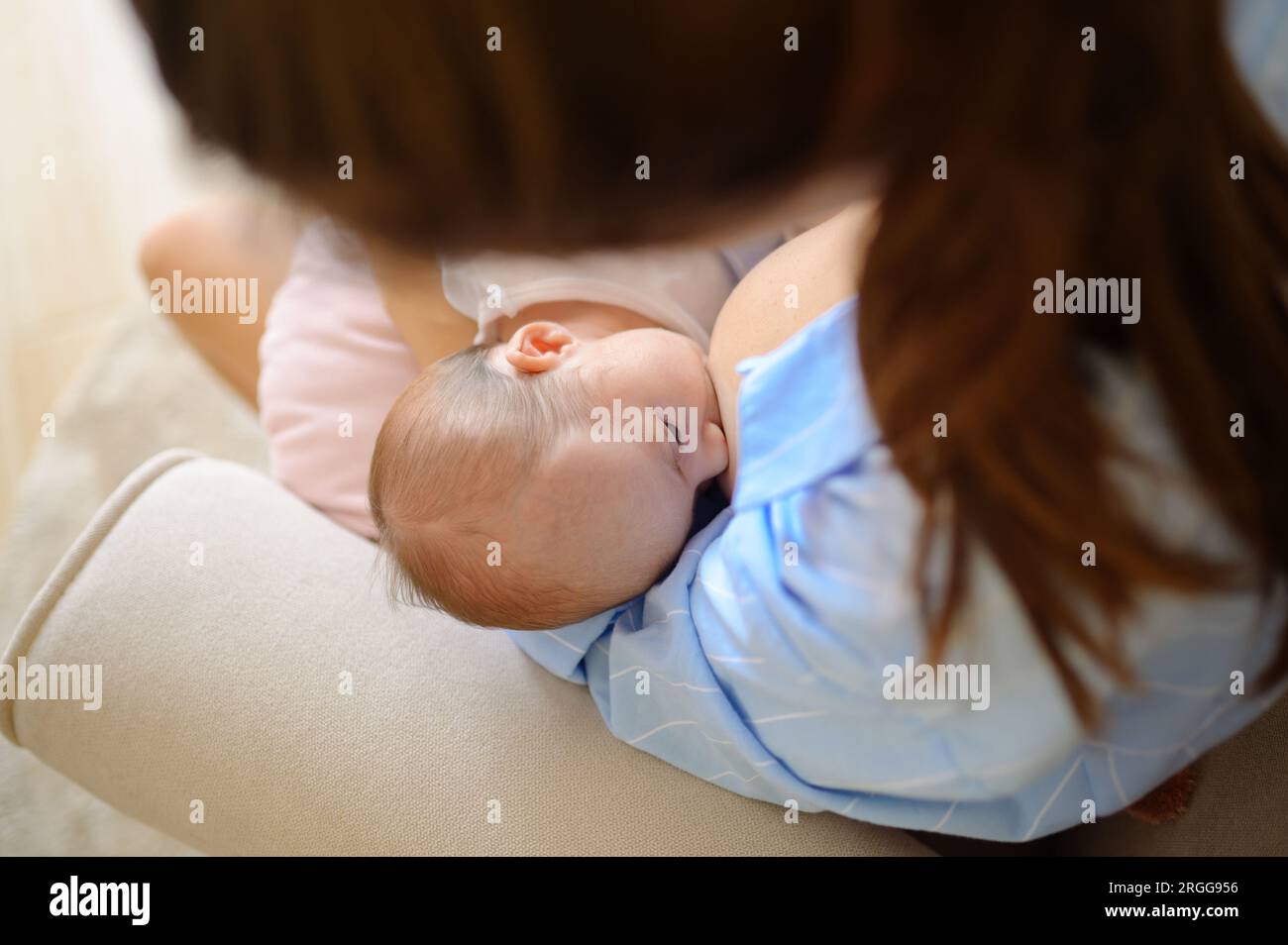 Mother feeding newborn baby in room Stock Photo