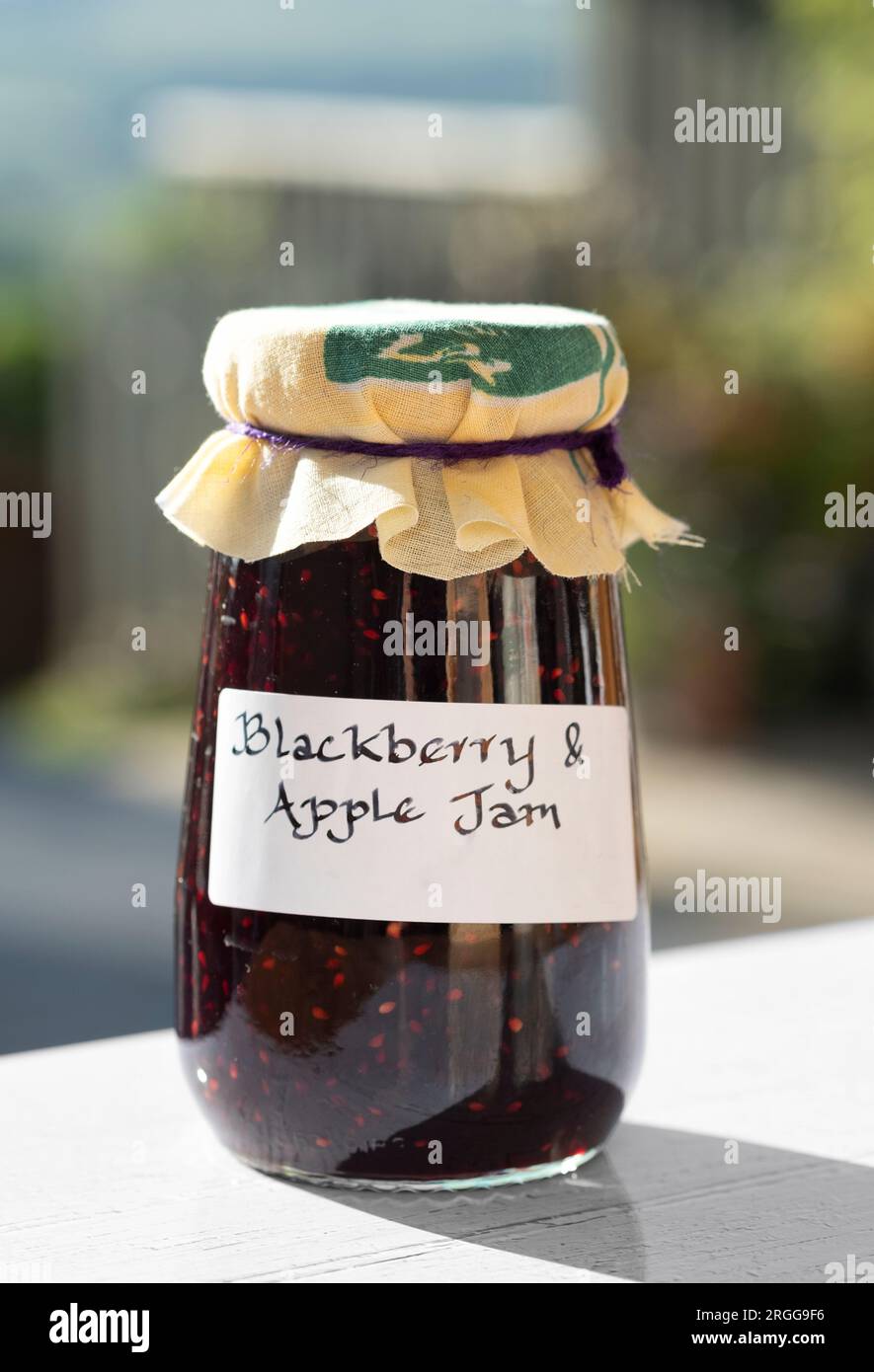 Jars of homemade Blackberry and apple jam. the jars have clear handwritten lables and the jars have a cloth topping Stock Photo