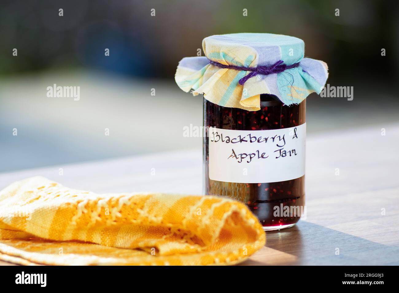 A Jar of homemade Blackberry and apple jam. the jar has a clear handwritten lable and  a cloth topping Stock Photo