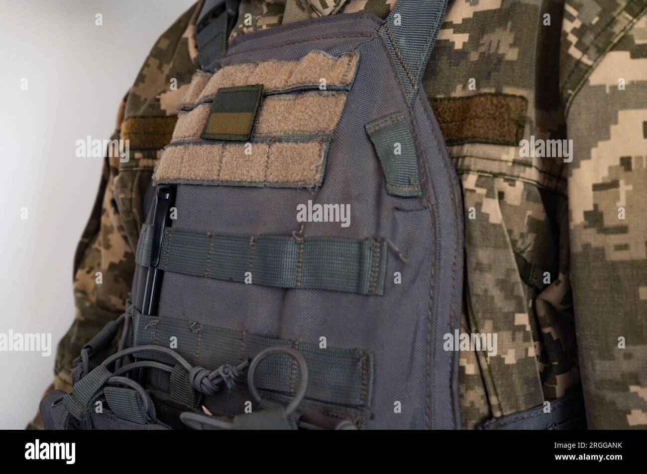 Soldier in grey bulletproof jacket with icon of ukrainian flag. Stock Photo