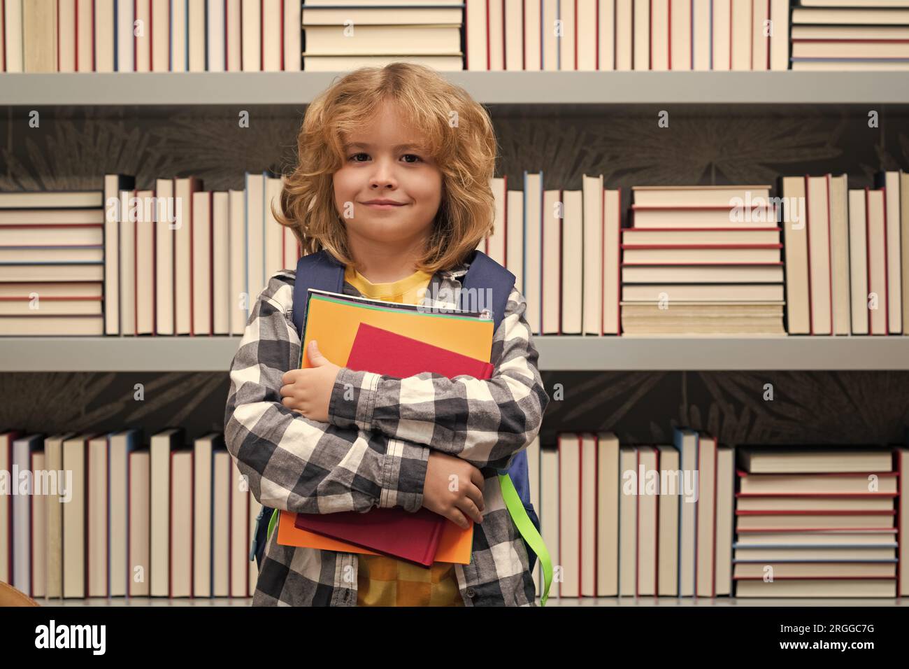 School boy with books in library. Back to school. Funny little child from elementary school with book. Education. Kid study and learning Stock Photo