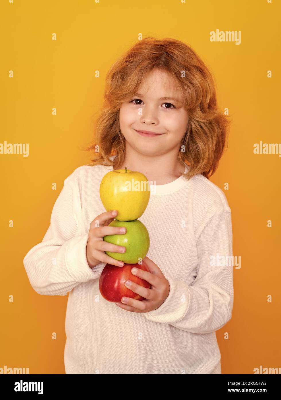 Vitamin and healthy fruits for kids. Kid with apple in studio. Studio portrait of cute child hold apple isolated on yellow background Stock Photo