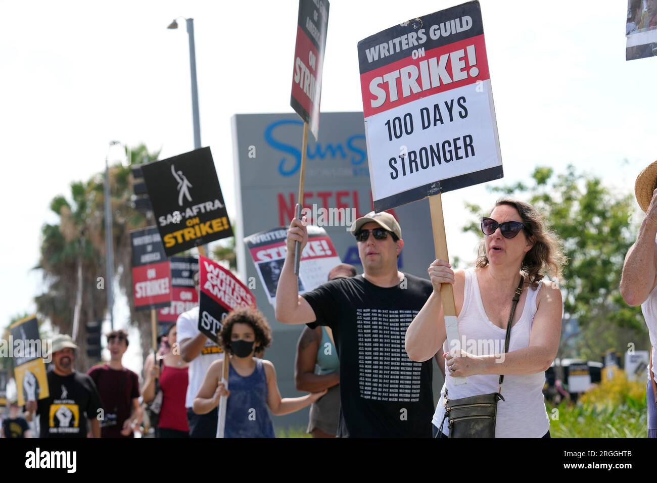 WGA member Emiliana Dore carries a sign on a picket line outside Netflix  studios on Wednesday, Aug. 9, 2023, in Los Angeles. The Hollywood writers  strike reached the 100-day mark today as