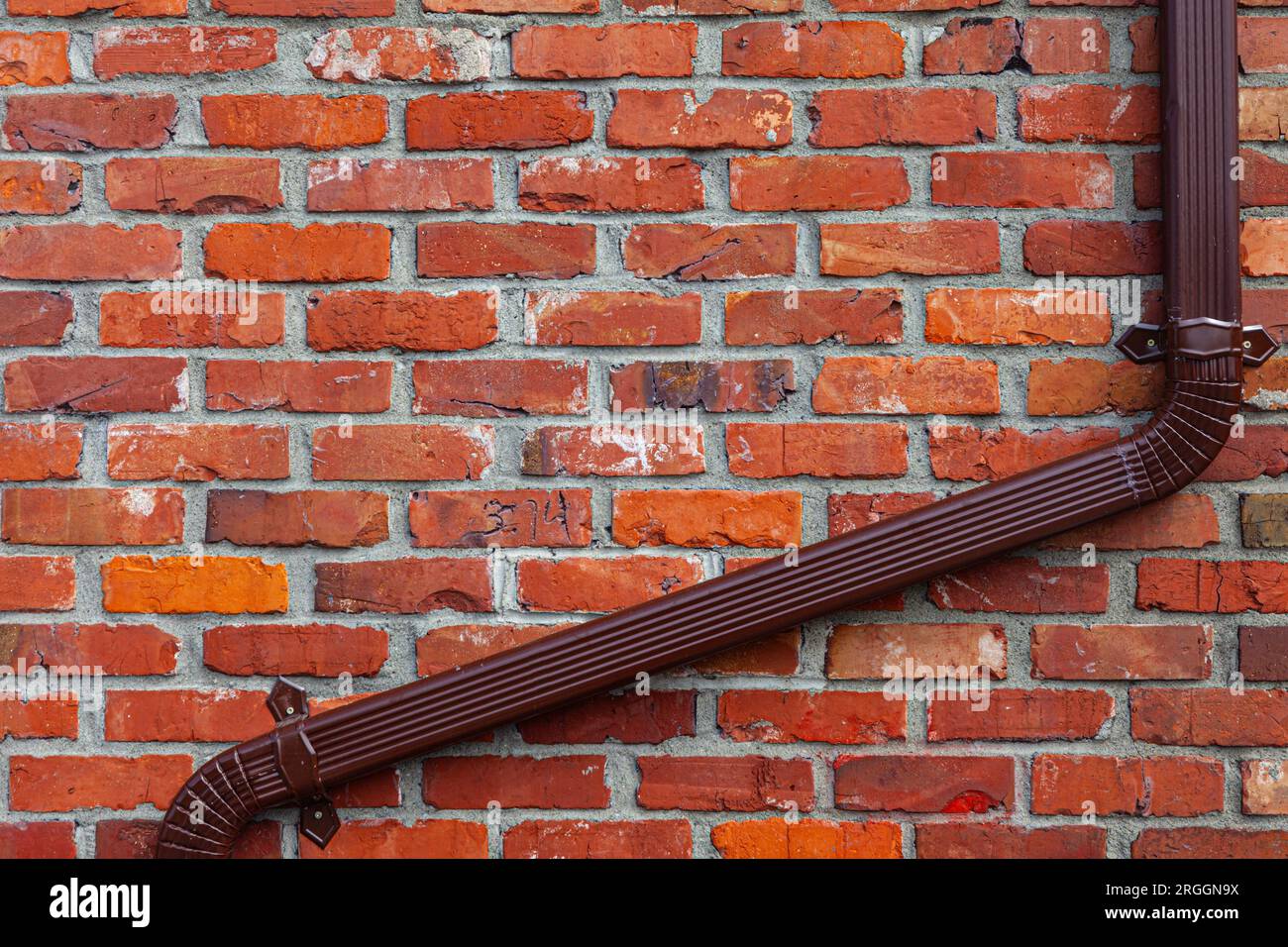Brown metal downspout fastened to a red brick wall Stock Photo Alamy