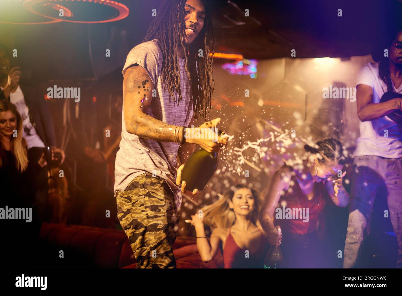 Young man spraying champagne at nightclub Stock Photo