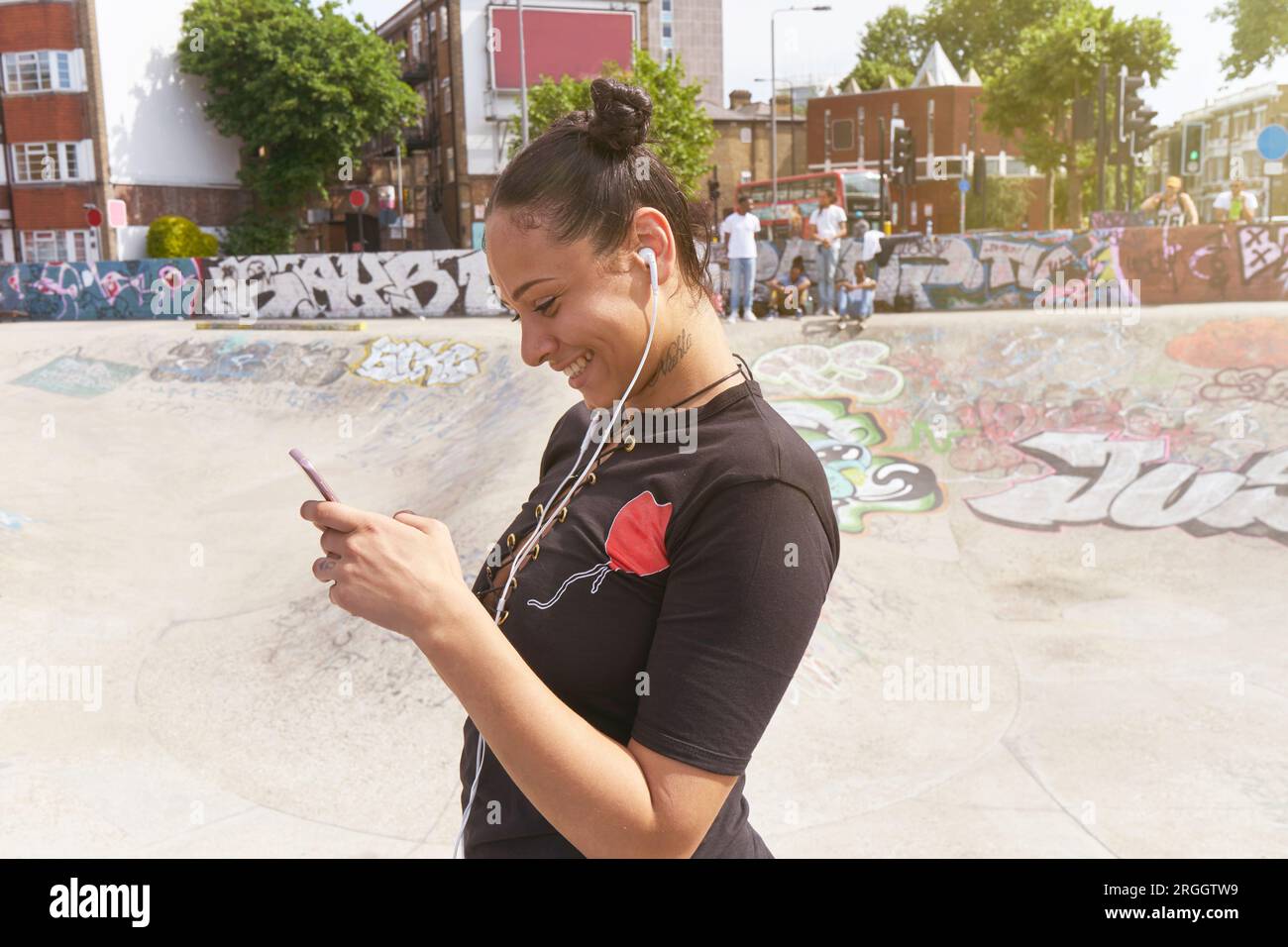 Young woman listening to music at skate park Stock Photo