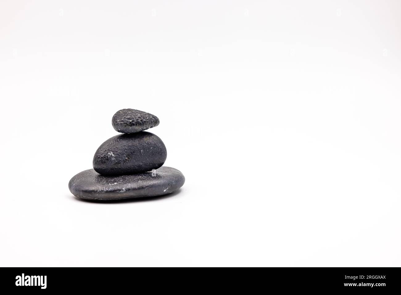 A cairn made of three black stones on white background cropped in studio Stock Photo