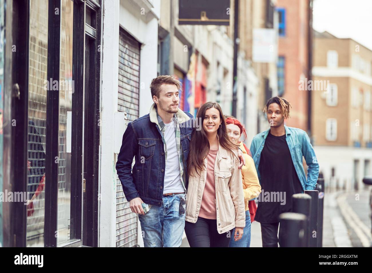 Teenage friends walking along street together Stock Photo