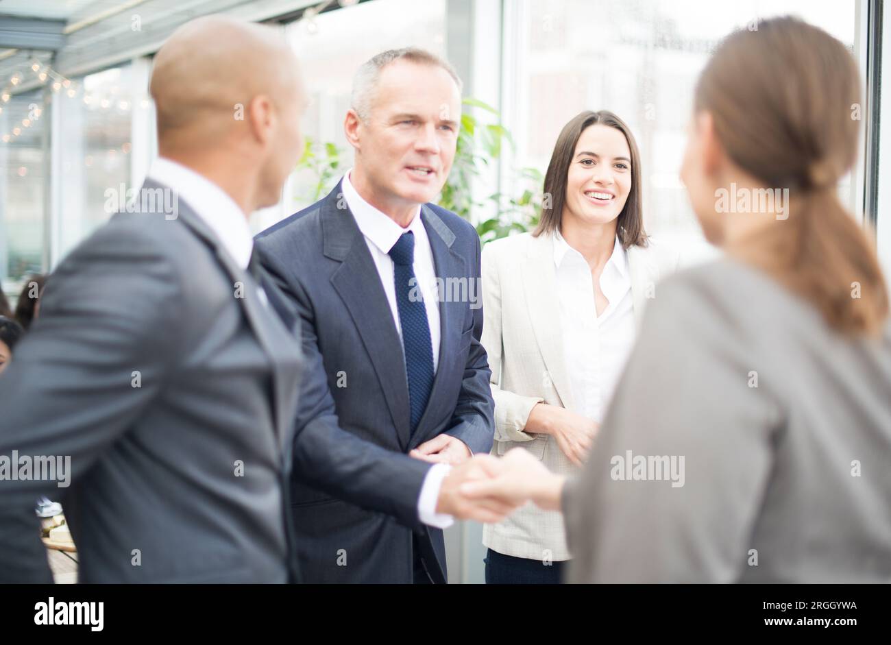 Businesspeople shaking hands by window Stock Photo