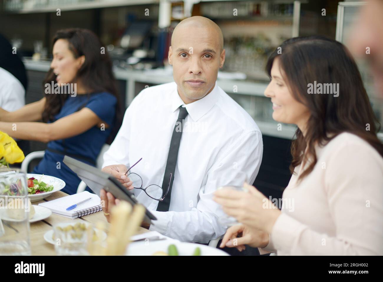 Businesspeople using tablet PC at restaurant meeting Stock Photo