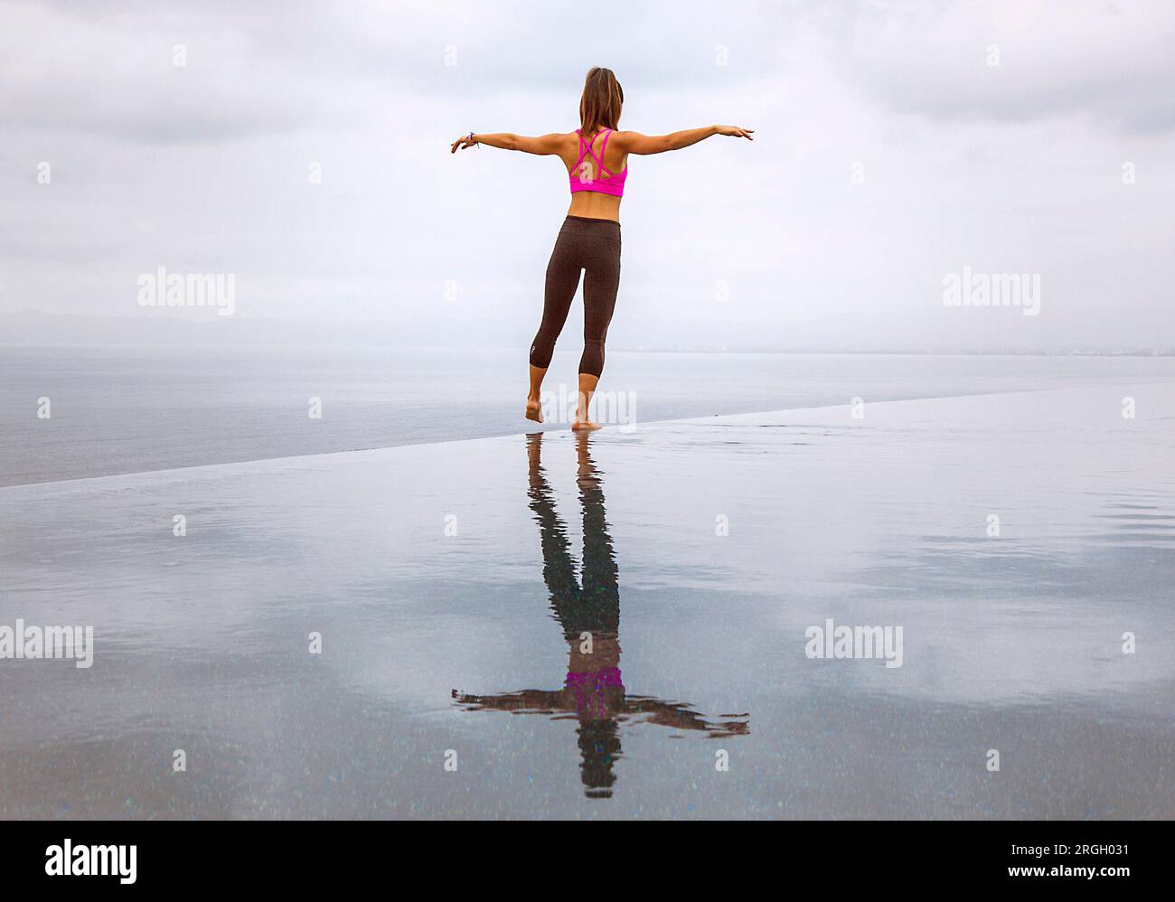 Woman standing with arms outstretched by the sea Stock Photo