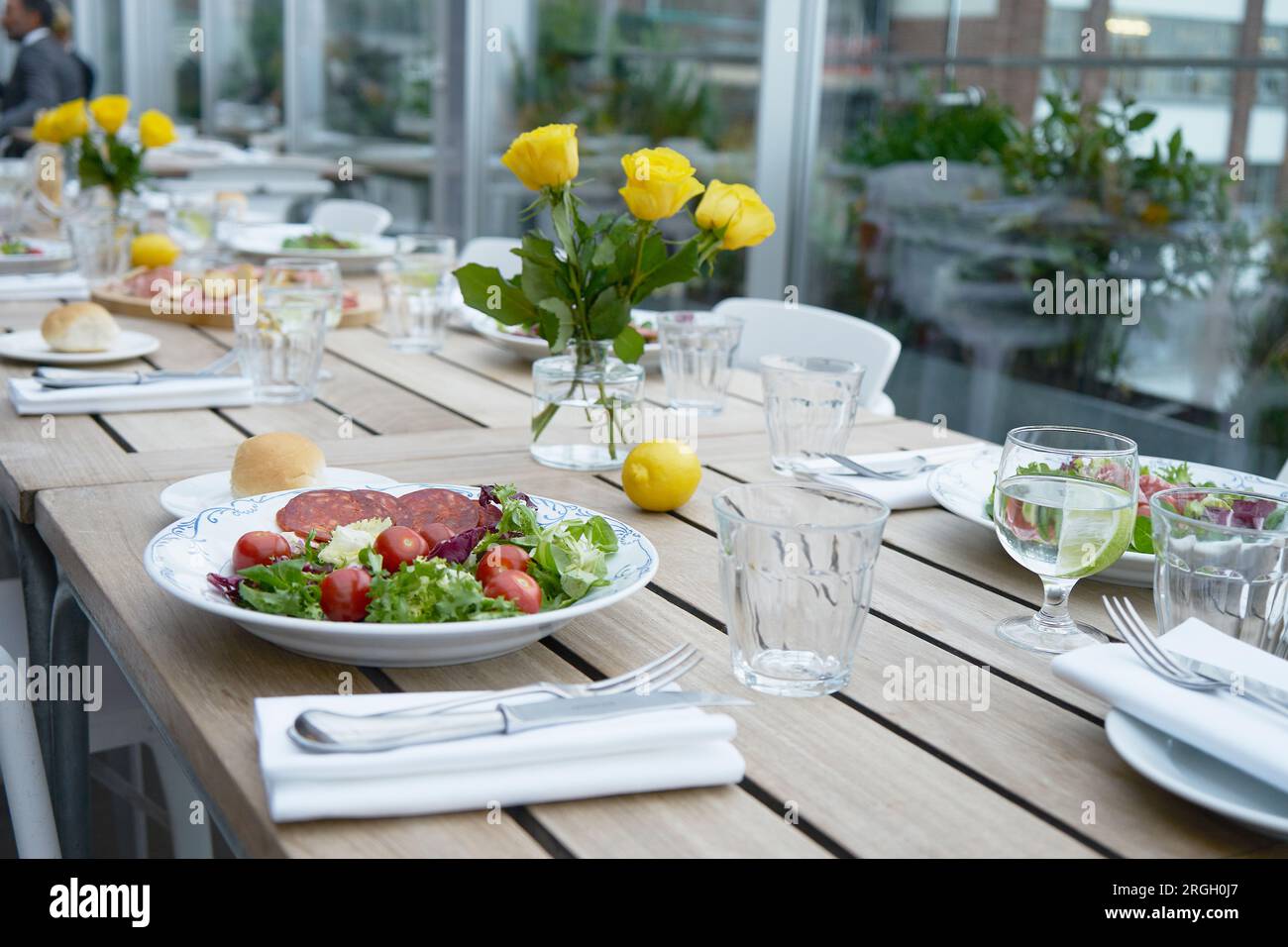 Salad on set table with yellow roses Stock Photo