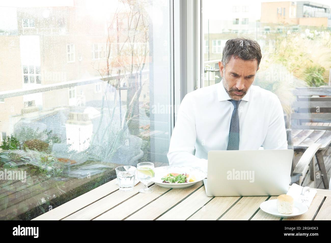 Businessman using laptop by window in restaurant Stock Photo