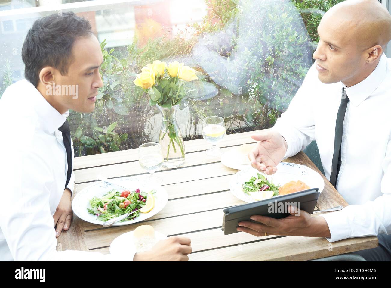 Businessmen using tablet PC during restaurant meeting Stock Photo