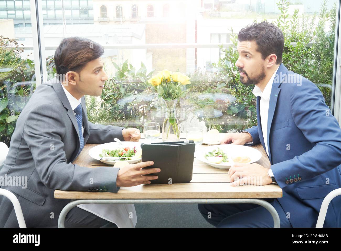 Businessmen using tablet PC during restaurant meeting Stock Photo