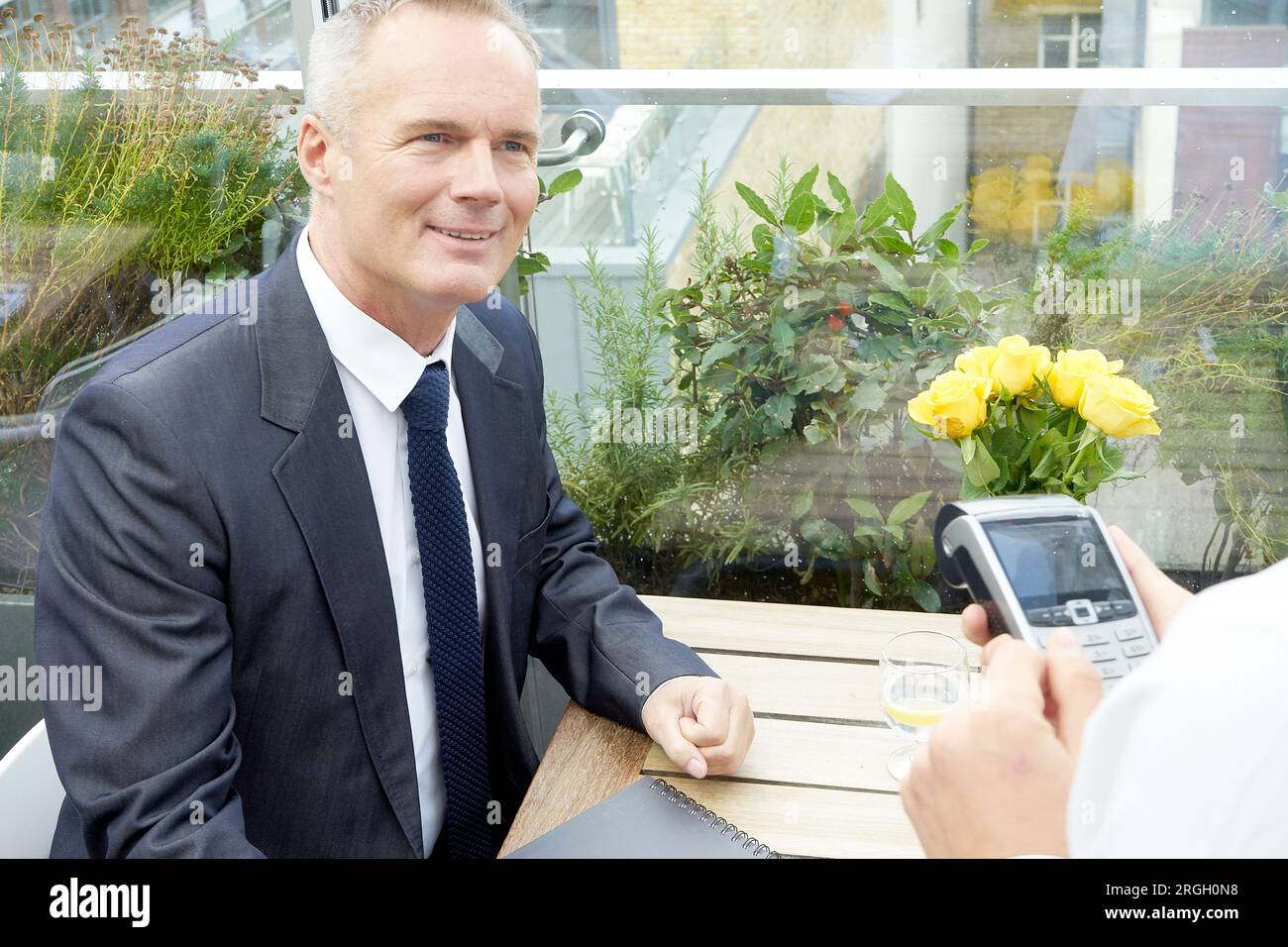Businessman using EFTPOS machine at restaurant table Stock Photo