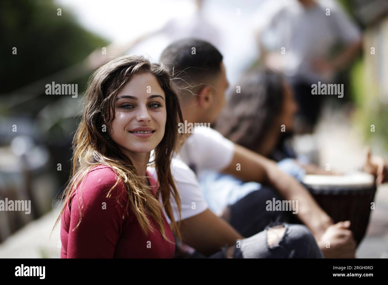 Young woman smiling outdoors with friends Stock Photo