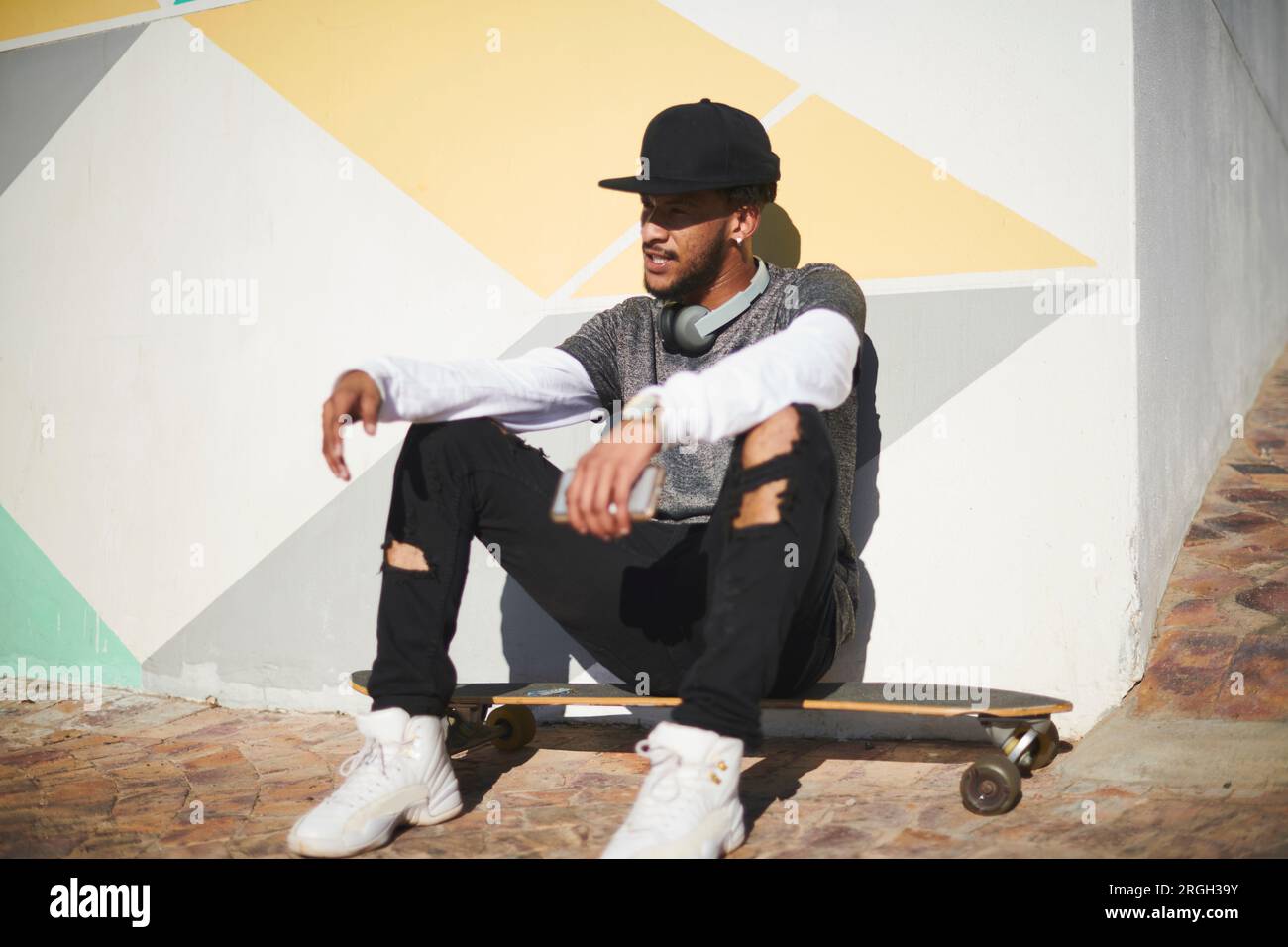 Young man sitting on skateboard Stock Photo