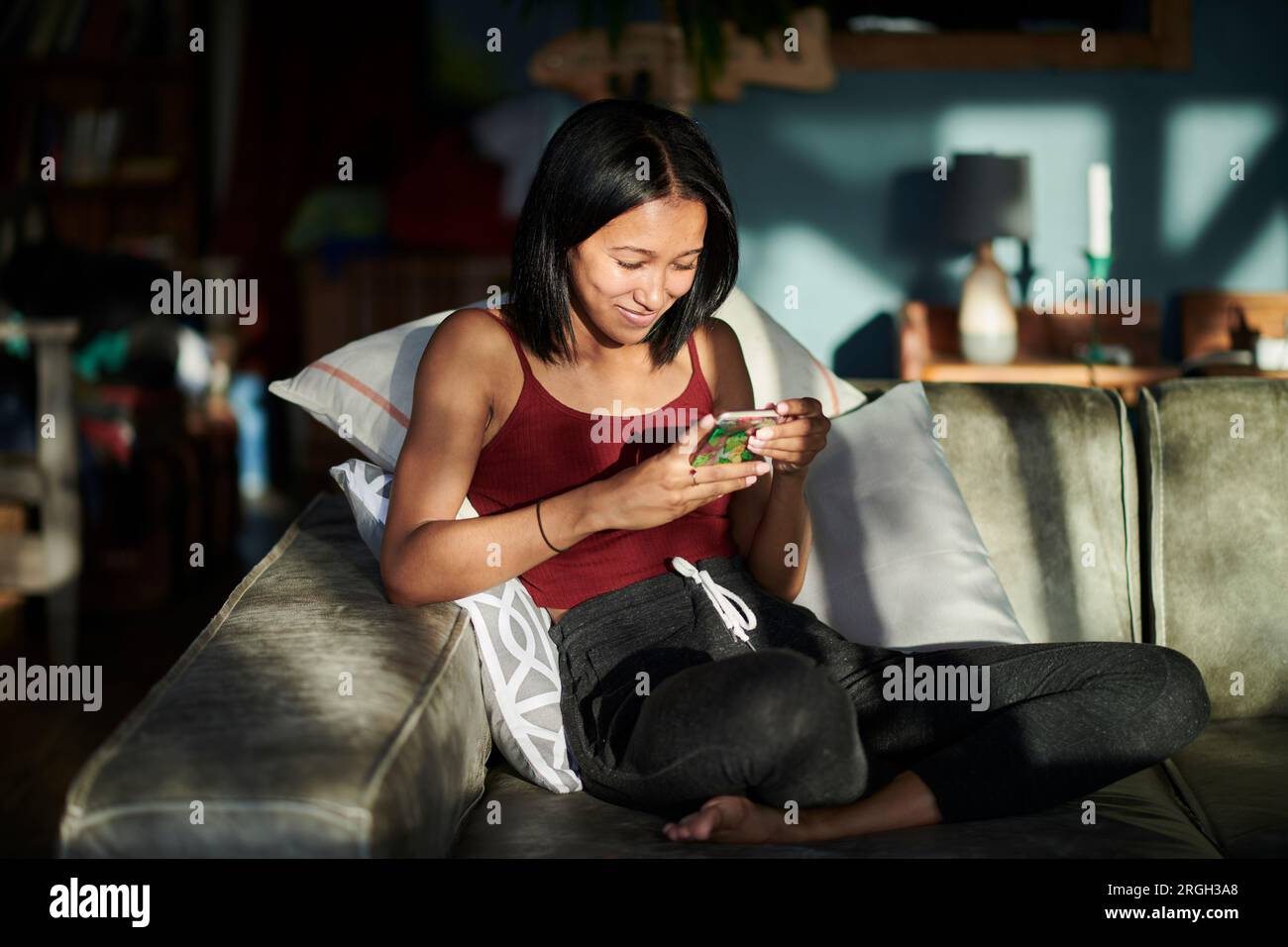 Young woman using smart phone on sofa Stock Photo