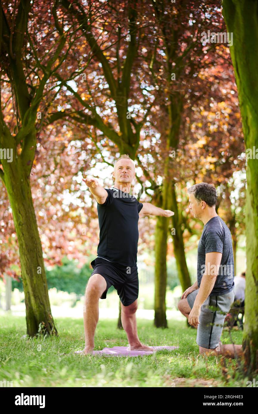 Mature men practicing yoga in park Stock Photo