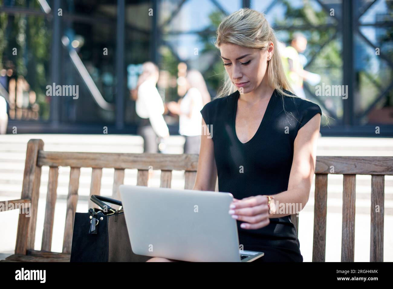 Businesswoman using laptop on bench Stock Photo